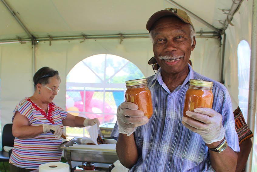 Deacon Whitfield Best holds up two of the last few bottles of his homemade West Indian hot sauce, minutes before they were sold at St. Philip's African Orthodox Church's annual Caribbean Festival on Monday. A family recipe, Best grew up watching his grandmother Lavinia Grant make the traditional sauce. Since the festival started in 1985, 84-year-old Best has been making his hot sauce for the jerk chicken dinners and to sell at the fundraiser. Bottles of his sauce usually sell out within the first 30 minutes of the event.