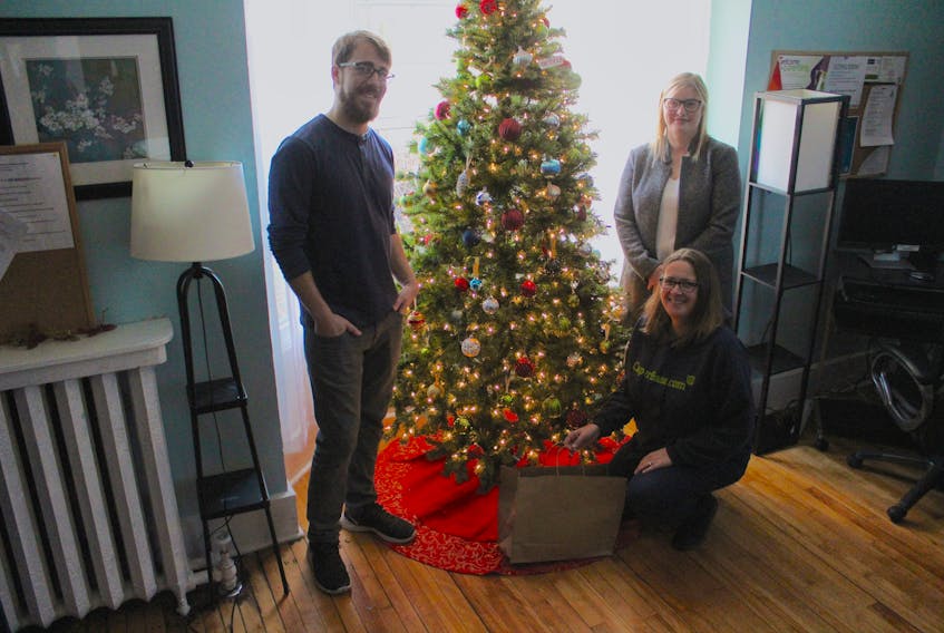 (From left) CaperBase staff Malcolm Campbell, Laureen Landry (kneeling) and Brandy Matheson stand near the Christmas tree at the Access 808 youth drop-in centre in Sydney, with one lone gift under it.  Donations can be made at Access 808 Monday and Wednesdays from 8:30 a.m. - 12 p.m./ 1p.m. - 4:30 p.m. and Tuesdays and Thursdays from 8 a.m. - 1 p.m. / 2 p.m. - 7:30 p.m. To find out more or to set up a donation drop off time call 902-539-7233. Access 808 is located at 808 George St., Sydney.