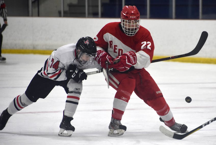 Ty Clarke of the Glace Bay Panthers, left, checks Logan Beaton of the Riverview Redmen during Cape Breton High School Hockey League playoff action Tuesday at the County Recreation Centre in Coxheath. Beaton scored the winner late in the third as the Redmen posted a 3-2 victory.