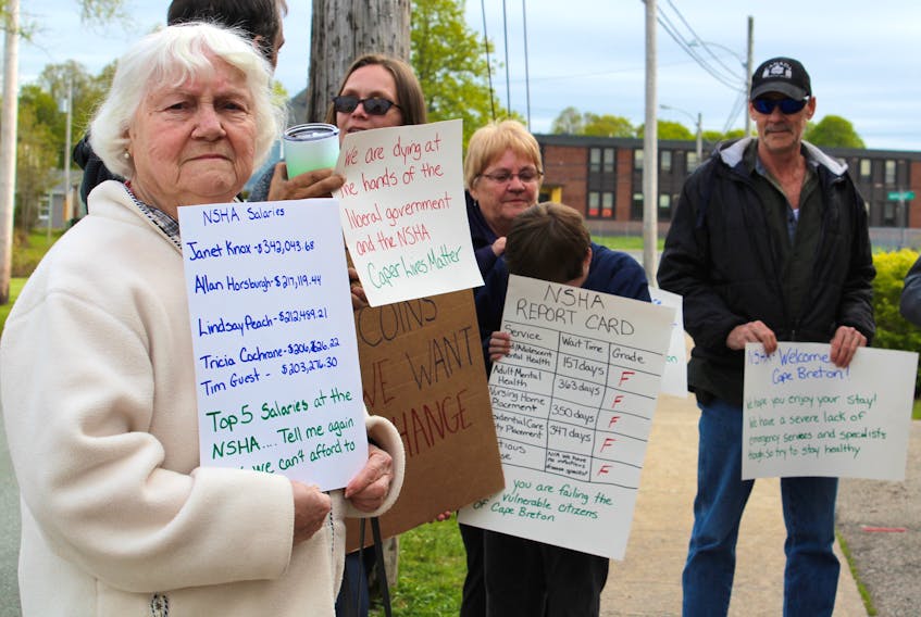 Flo Gwinn, 83, of North Sydney holds a sign Wednesday during a demonstration outside a meeting hosted by the Nova Scotia Health Authority at the North Sydney Firefighters Club.