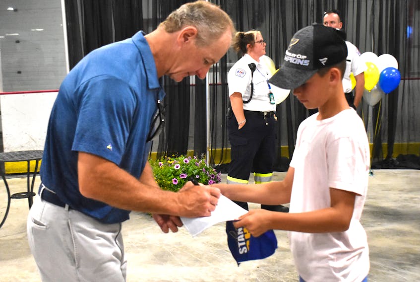 Al MacInnis, left, signs an autograph for Ben MacDonald of Port Hood during the Stanley Cup celebration in Port Hood on Saturday. MacInnis spent hours signing autographs and posing for photos with fans throughout the day.