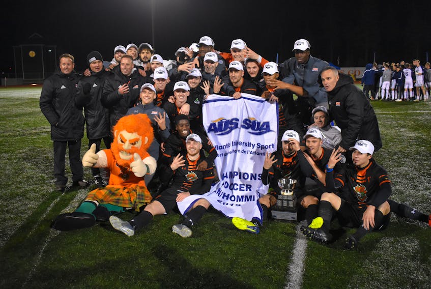 The Cape Breton Capers men’s soccer team are shown with the Atlantic University Sport championship banner and trophy following their 2-0 overtime win over the St. Francis Xavier X-Men in the league final at Cape Breton Health Recreation Complex turf on Sunday. The Capers will begin the 2019 U Sports men’s soccer championship today against Calgary.