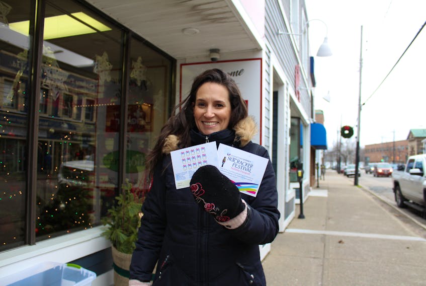 Michelle Wilson, executive director of the Sydney Downtown Development Association, poses with downtown passports on Charlotte Street, Sydney on Friday. The passports and free weekend parking are among the incentives on the go with a goal to increase downtown traffic during the holiday shopping season.