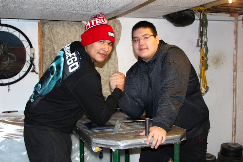 Cousins Dre Denny (left) and Liam Johnson get ready to arm wrestle in the basement of their aunt's home in Eskasoni First Nation on Jan. 6. The two 18-year-olds are Canadian national arm wrestling champions who competed in the IFA World Arm Wrestling Championships in Poland, Dec. 5-6, where Johnson came third in right-arm and got to hold the Canadian flag on the podium. Arm wrestling might be in their blood. Their uncle Stephen Sanipass is credited for bringing the sport to Eskasoni and his sons, Trevor, Joseph and David, have all medaled at various championships.