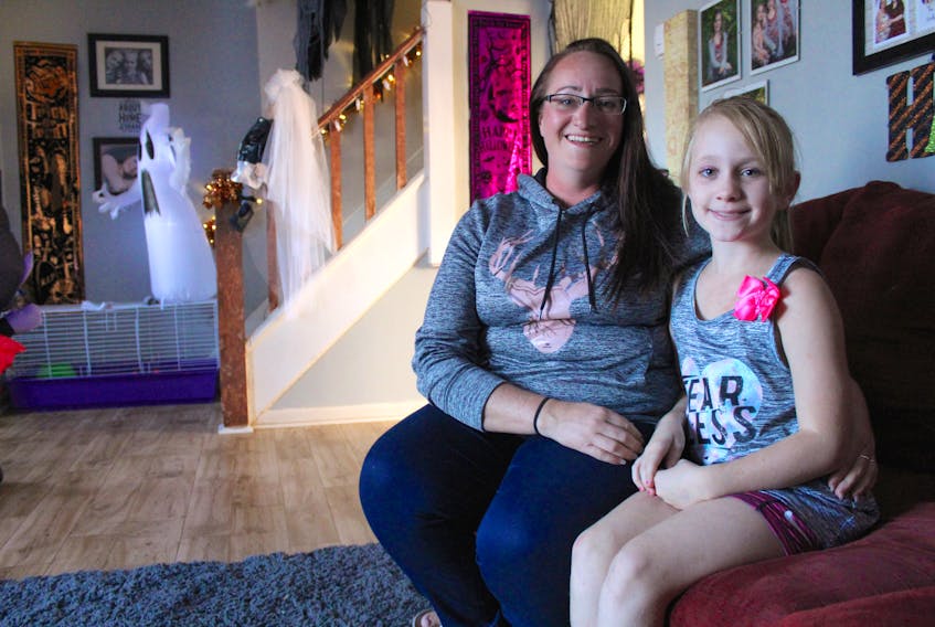 Amy LeTournal sits with her 10-year-old daughter Rebeccah (Beckie) MacDonald in the living room of their Glace Bay home, which is decorated for Halloween, on Oct. 6. In September, Beckie was riding her bike in her neighbourhood when she was the victim of a hit and run. LeTournal said she is thankful her daughter wasn't badly hurt but the incident has brought back her own memories of landing in hospital after being hit by a driver who left the scene.
