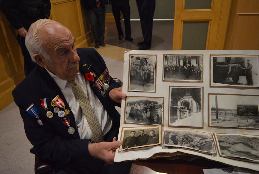 Second World War veteran Charlie Palmer looks over some of his personal photos from the war in this file photo. SUBMITTED PHOTO