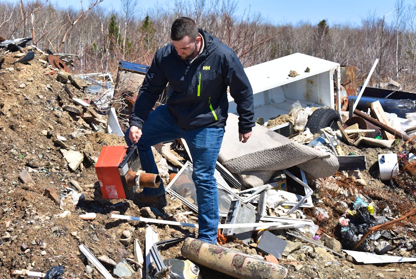 Dylan Yates, founder of the Cape Breton Environmental Association, picks up a burner unit from a furnace he found buried in the mounds of garbage that has been illegally dumped behind the water tower in Reserve Mines. Along with furnace pieces are vehicle parts, oil tanks, refrigerators and stoves.
