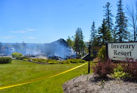 The sign at the front entrance to the Inverary Resort in Baddeck is shown on Thursday afternoon, with the still-smouldering remains of the resort’s main building in the background.