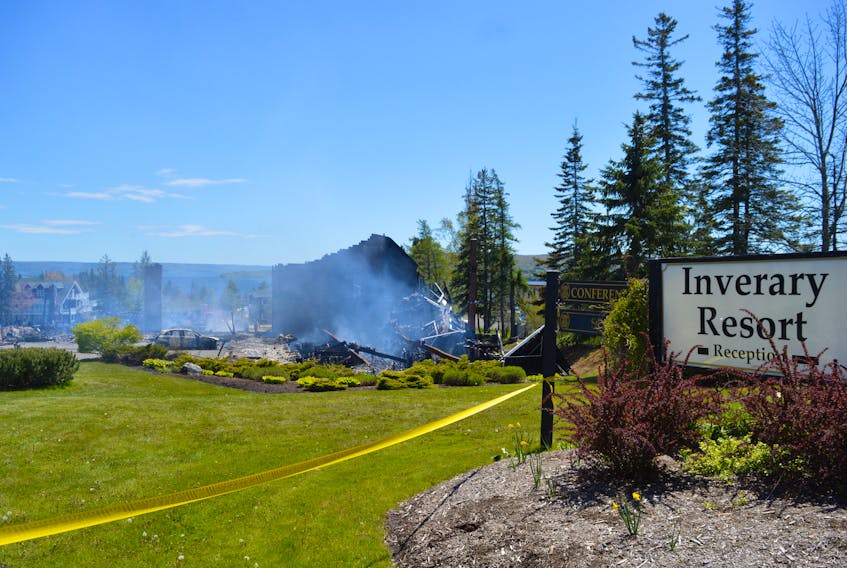 The sign at the front entrance to the Inverary Resort in Baddeck is shown on Thursday afternoon, with the still-smouldering remains of the resort’s main building in the background.