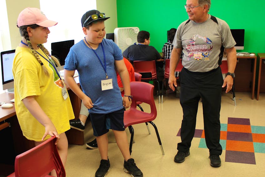 Gary Walsh, right, director of Acadia University Robotics, congratulates IBM STEM youth summer camp participants Liela Doucette and Bryson Morrison on successfully instructing their robot to move forward through the use of a computer program. It’s the first time the science and technology camp, hosted by IBM, has been held in an Indigenous community in Cape Breton.