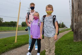 Siblings Bradley MacNeil-Burke, Ella Jessome and Brian Jessome are shown waiting for the school bus to take them to Coxheath Elementary and Riverview High on Tuesday, the first day of school for students in the Cape Breton Victoria Regional Centre of Education.