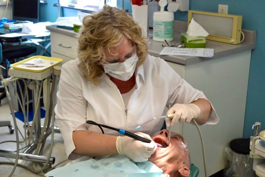 Dental Hygienist Natalie Mulak works on patient Keith Ballam of Sydney during a free dental clinic held in Whitney Pier on Saturday. More than 100 similar clinics were held across Canada as part of the national Gift From The Heart program.