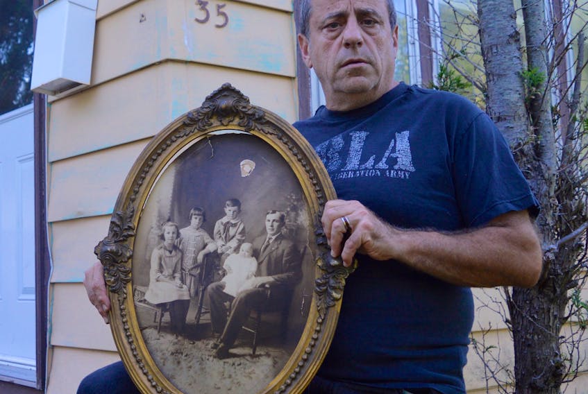 Chris Abbass holds up an old portrait of what appears to be a man and his four children that he found in the attic of his north end Sydney house. Abbass is hoping someone can help him identify the people in the photograph and reveal what happened to them.