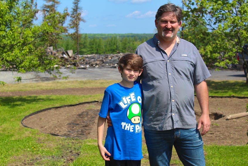 Carter O’Brien (left) stands with his father, Greg O’Brien, in front of the charred remains of their home and bed and breakfast. Carter, 11, was in the house with his mother when the blaze started and the two were able to get out safely with the family cat and dog. Greg, who was working in Saskatchewan when the fire started, says happy doesn’t describe how he feels about his family escaping the blaze unharmed.