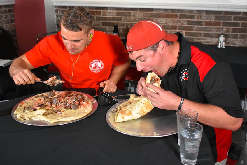 Sydney resident Joel Hansen, left, and professional eater and bodybuilder Randy Santel chow down during their attempt to successfully eat a six-pound donair in less than 28 minutes and 30 seconds, the time it took Hansen to complete the task in May. With an encouraging crowd looking on, Hansen devoured his donair in 14 minutes and 39 seconds, while Santel gobbled the last of his meal down five seconds later.
