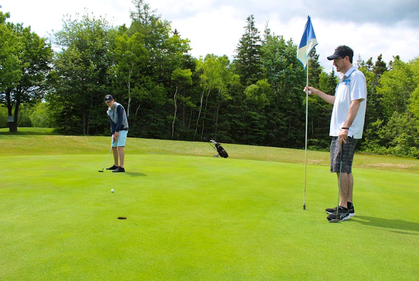 Bryson McNeil attempts a putt at Lionel’s Gardiner Greens Golf Course on Wednesday morning as his father Shane looks on. The two were taking advantage of good golf weather to get in nine-holes. Shane’s been golfing for a while but this is Shane’s first year trying the sport.