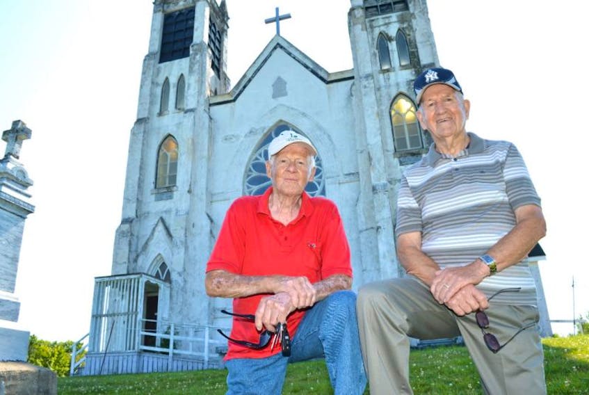 Friends Martin MacKinnon, left, 91, of South Bar, and Mike Campbell, 91, of New Victoria, gather together in front of the former St. Alphonsus Church where both were not only life-long members but were married there and now have their wives buried there. MacKinnon and Campbell said it was sad to see the church close but they were happy the Stone Church Restoration Society has saved it and hope the society gets access to it soon.