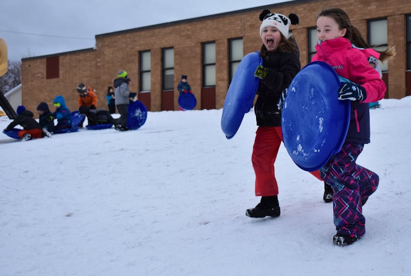 Stori Corbett, 8, left, and Lydia Jarrett, 8, take a running start before jumping on their sleds at Robin Foote Elementary on Thursday. Last year, the school bought sleds for students to use during recess and lunch breaks. The students love it and so do the teachers, who say students pay more attention in class after spending their break sledding.