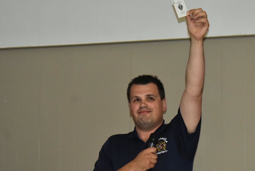 Margaree firefighter Jason McDaniel holds up the ace of spades after picking for winners Barb Reddick and Tyrone MacInnis, who weren’t in attendance. The pair, who couldn’t be immediately reached by phone, will split the $1.2-million prize.