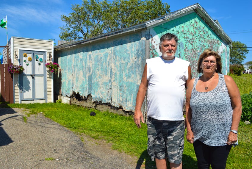 David Reid and his wife Carla Reid of Walsh Avenue in New Waterford show how close a delipidated barn at the corner of King Street and Walsh Avene is to their baby barn. The couple says the barn, which is slated for demolition, is a fire hazard and rat magnet.