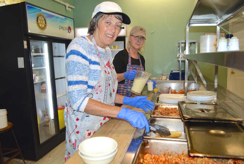 Bibiane Lessard, left, and Trish Caines, volunteers with Loaves and Fishes soup kitchen and food bank in Sydney, were busy serving hot meals to people coming in Wednesday. General manager Marco Amati said numbers for their hot meals have gone way up in the aftermath of the recent tropical storm.