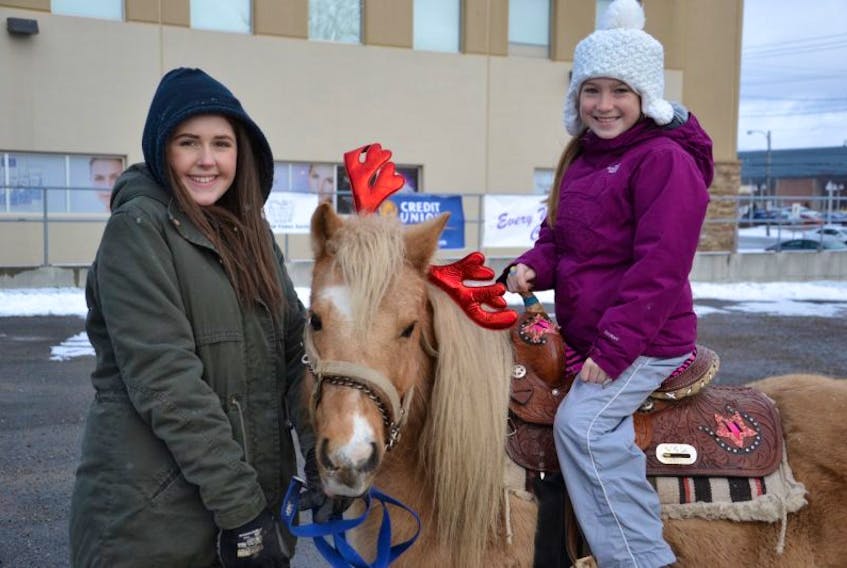 Pony rides were offered at the first annual Christmas Cheer event on Saturday to raise money for Loaves and Fishes and Every Woman’s Centre. Shown here, left right right, are volunteer Nicole McNeil, Goldie the pony and Colby Lynk, 8, of Reserve, who owns Goldie.