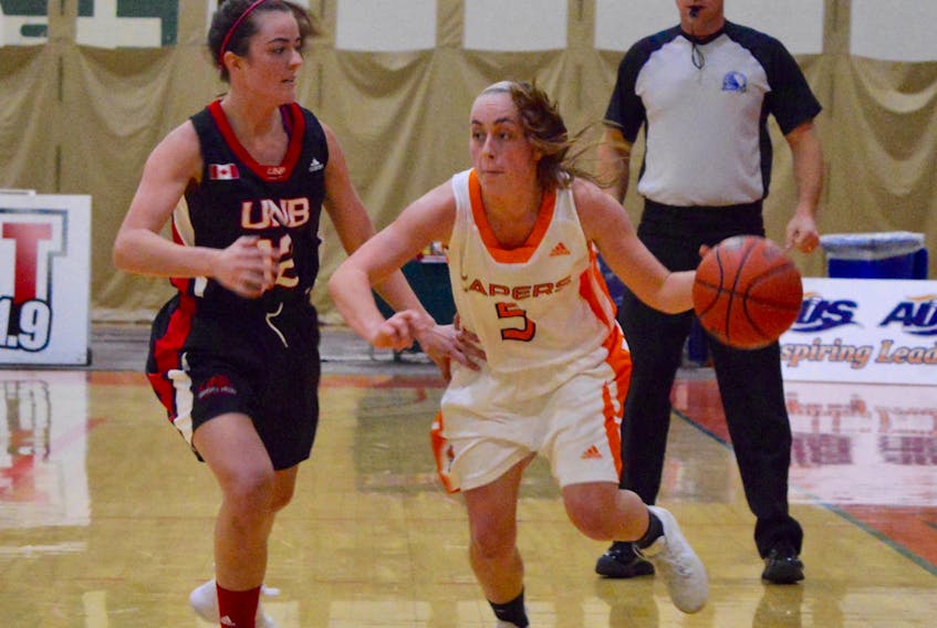 Toni Bianchini, right, of the Cape Breton Capers makes her way around Nicole Esson of the University of New Brunswick Varsity Reds during Atlantic University Sport basketball action at Sullivan Fieldhouse in Sydney, Friday. The Varsity Reds won the game 90-83 in overtime.