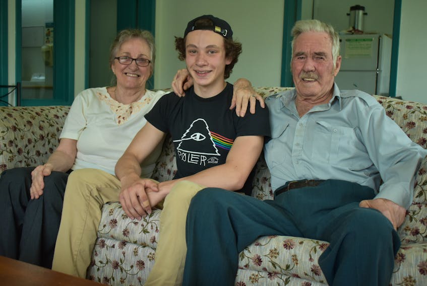 Avery Gale, centre, sits beside Mary Cross and Kenneth Cross in the common room of the senior apartment building in Marion Bridge the couple live in. The 16-year-old saved Kenneth, 90, from drowning on Sunday after he lost his balance and fell off the community dock.