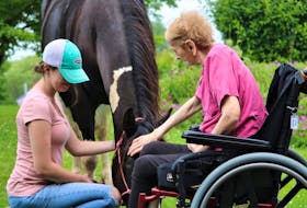 Caitlin Carter, left, holds her horse Breagha while R.C. MacGillivray Guest Home resident Francis Waters pets its nose. Facility recreation director Kim Hooper said Waters rarely takes part in activities but was so excited to see the horses she decided to come down from a nap.
