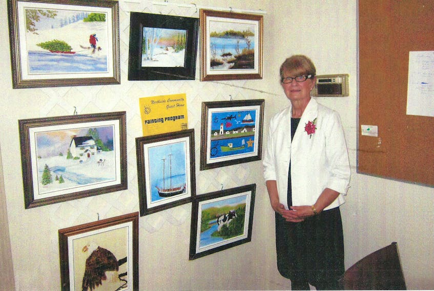 Erma Carmichael stands next to a gallery of paintings completed by seniors through a program she founded at the Northside Community Guest Home.