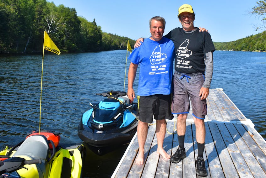 Craig MacNeil, left, and Gord MacDonald stand on a Georges River dock a short time after completing their two-day trip around Cape Breton Island. But, what made the journey so special was that they accomplished the feat on a pair of Sea Doos. MacDonald, who owns Gord’s Sports Centre Racing Ltd. in Sydney, rode the 300-horsepower lime coloured machine, while MacNeil was on the not-quite-as-powerful 250-horsepower blue Sea-Doo.