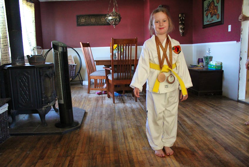Neveah Beevor, seven, proudly wears her Integrity Martial Arts taekwondo uniform, yellow belt and two bronze medals she won at her first competition. Since starting at Integrity Martial Arts in December, the Greenfield Elementary student has gained confidence, happiness and movement in her right hand, which was partially paralysed because of a stroke she had at six-months-old.