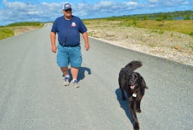 John MacPherson, a firefighter with the Cape Breton Regional Fire Services and volunteer firefighter with the Glace Bay Volunteer Fire Department, walks his dog Murphy along the Donkin Coal Road, which is under construction. Construction on the road suddenly stopped about a month ago, leading to speculation the project was on hold. However, officials with Nova Scotia Power, involved in the project installing new power poles, say there’s about a month delay due to them having to get easements for the new poles which is a timely process. MacPherson said he loves the road, which sees a lot of activity on the weekend including people walking, jogging, out with ATVs and even fishing.