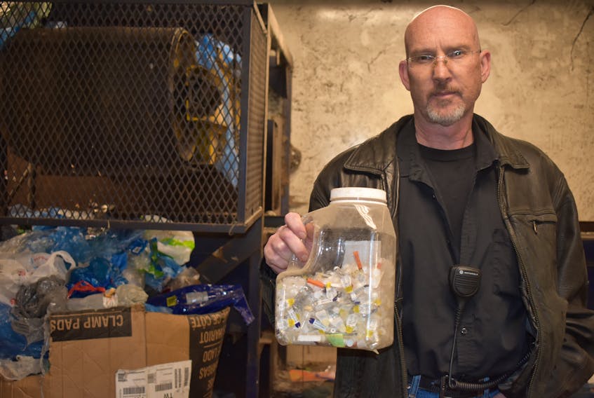Jeff Strong, operations supervisor at Camdon Recycling in Sydport, holds a bottle of needles and lancets staff have found recently while sorting through materials. Nikki Sullivan/Cape Breton Post