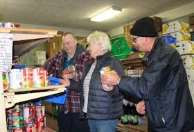 From the left, Carmen Hood, Sally Ryan and Calvin Gillard stock the shelves at the North Sydney Community Food Bank. These days officials at the food bank are preparing for Christmas orders and activities.