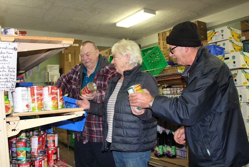 From the left, Carmen Hood, Sally Ryan and Calvin Gillard stock the shelves at the North Sydney Community Food Bank. These days officials at the food bank are preparing for Christmas orders and activities.