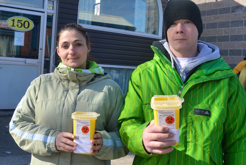 Amanda Williams and Shane Burton, volunteers with the Ally Centre of Cape Breton, hold small safe sharp containers for disposal of needle litter. The two were walking around downtown Sydney on Wednesday on the lookout for used needles in public places so they could dispose of them correctly.