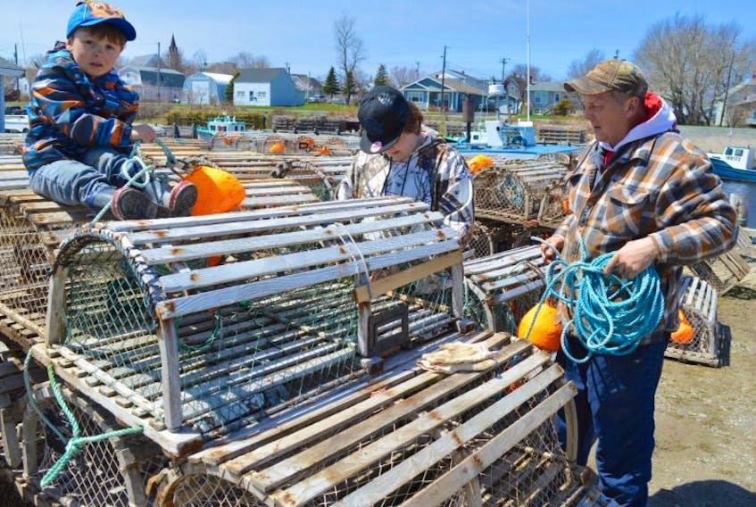 Fisherman John Thomson, right, of Glace Bay checks traps with help from sons Jackson, 3, and Ryan 13, while at Glace Bay harbour to prepare his boat Natasha Lee II for the season, which opens Wednesday in Area 27.
