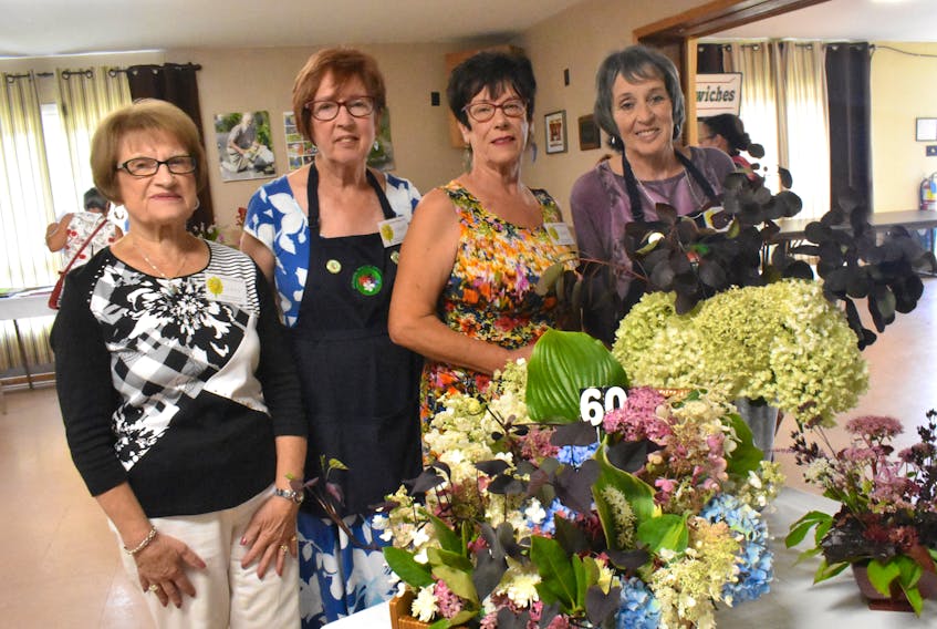 Among the organizers of the Westmount Garden Club's 60th anniversary celebration showcase were Lucy Nardini, from left, Janet Elsie, Barbara Boutilier and Bibiane Lessard who posed in front of an arrangement made to mark the milestone by Annette Purcell. As part of the Saturday afternoon festivities, the public was invited to learn more about flowers and view displays and arrangements. Door prizes, tea and light refreshments were provided, while visitors could ask local garden club members questions about the local growing season.