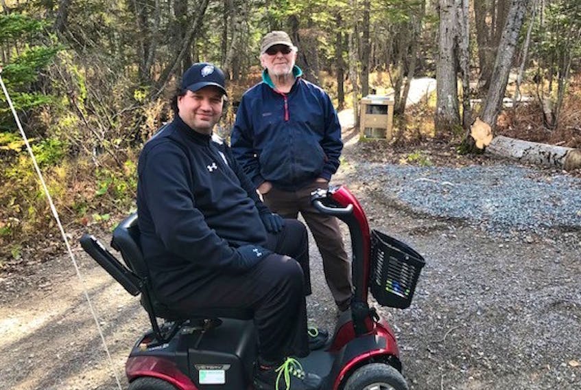 Robert Zwarun is seen travelling the Baille Ard Trail in his motorized scooter on Nov. 2 while an unknown passerby looks on. It was the first time the 47-year-old Sydney resident, who has an inherited degenerative disease, had ever been in a forest and he describes it as a life-changing experience.