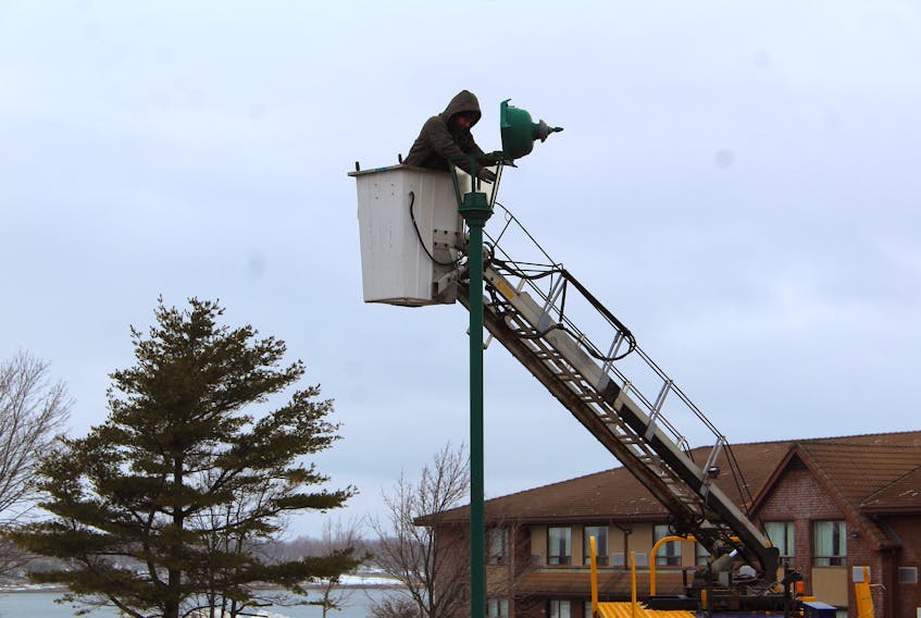 John Forget is shown updating the lighting high above the Sydney Service Nova Scotia building parking lot on Friday. The Employee of 7-Signs was switching the light bulbs to LED and changing lenses they custom made at their shop. He was working on light five of eight when this photo was snapped.