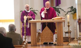 Rev. Bill Burke, right, holds up the chalice holding a liquid that symbolizes the blood of Christ during communion at St. Marguerite Bourgeoys church on Sunday.