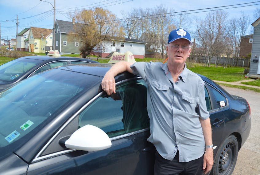 Michael MacGillivary, owner and driver with Marg’s Taxi in Glace Bay, stands by one of the company vehicles outside their base. MacGillivary said the main concern for taxi drivers today is the unknown they are heading to.