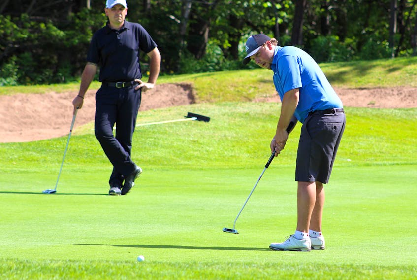 Kevin George, right, is shown attempting a putt on the No. 9 hole of the Lingan Golf and Country Club on Sunday, while Ryan Boutilier, left, watches. Both were participants in the Cape Breton Roadbuilders tournament, which George went on to win.