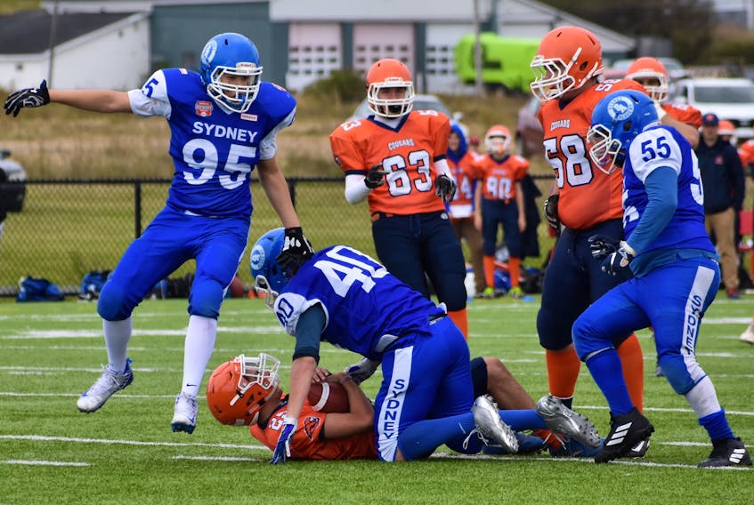 Sydney Academy Wildcats defenders Dylan Graham (#95), left, and Nore Shullaih (#55), right, arrive on the scene only to find that teammate AJ Wincey (#40) has already brought down Cobequid Education Centre Cougars running back Matt Shannon for a loss during a Nova Scotia School Athletic Federation football game. About 200 fans took in the game that was played at Sydney’s Open Hearth Park field on a cool and drizzly Sunday afternoon. It was the season opening match for both teams after last weekend’s games were cancelled due to stormy weather across the province. CEC won the game, 28-9.