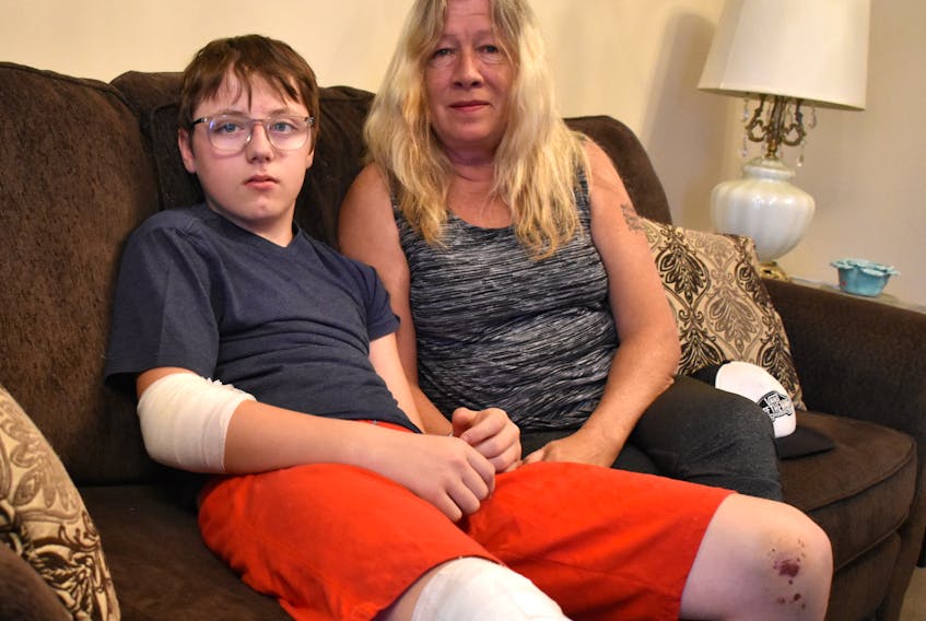 Stephen Wall, 14, sits with his grandmother Leanne McCarthy in their Whitney Pier home on Oct. 12.  The Sydney Academy student is bandaged up after being hit by a vehicle on Oct. 8 while using the lit crosswalk at the Welton and Reeves streets intersection in Sydney. While the driver did stop and ask how Wall was, he left after the teen said he was fine even though Wall was bleeding and his clothes were ripped. McCarthy hopes with the public’s help they can locate the driver.