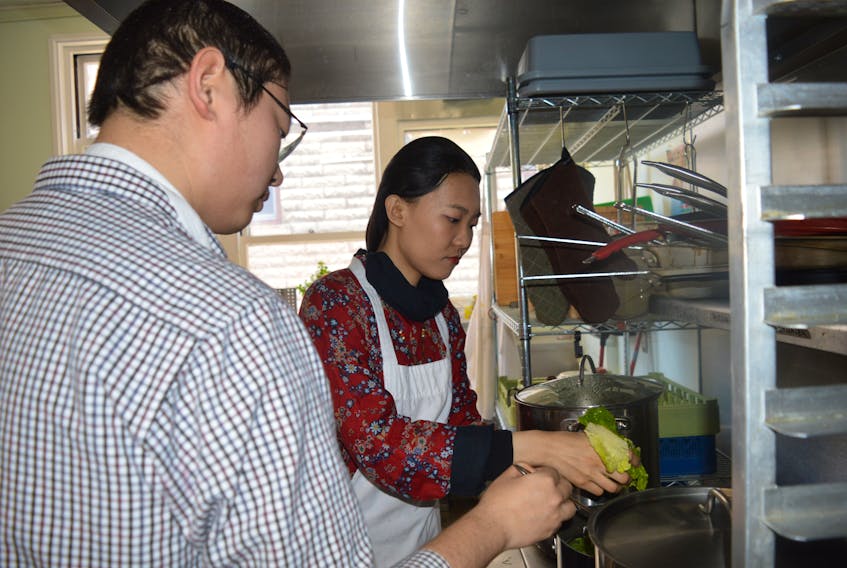 Jonathan Fang and Sophia Zixuan Yang are showing preparing wonton soup for meals on wheels clients in Sydney. The Cape Breton University students added the soup to the regular meal delivery as part of the Chinese New Year.