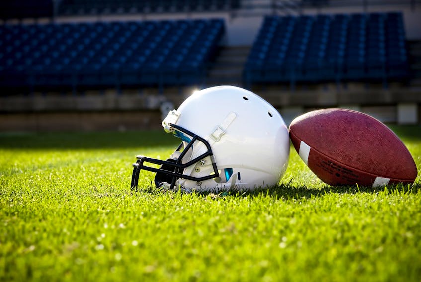 A football and helmet on a football field.