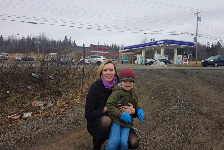 Jennifer Anderson and her son Anderson Green kneel down near the end of their driveway, located directly across from the Irving/Tim Hortons location on Highway 105 in Baddeck. Jennifer Anderson has concerns about construction scheduled for area this summer.