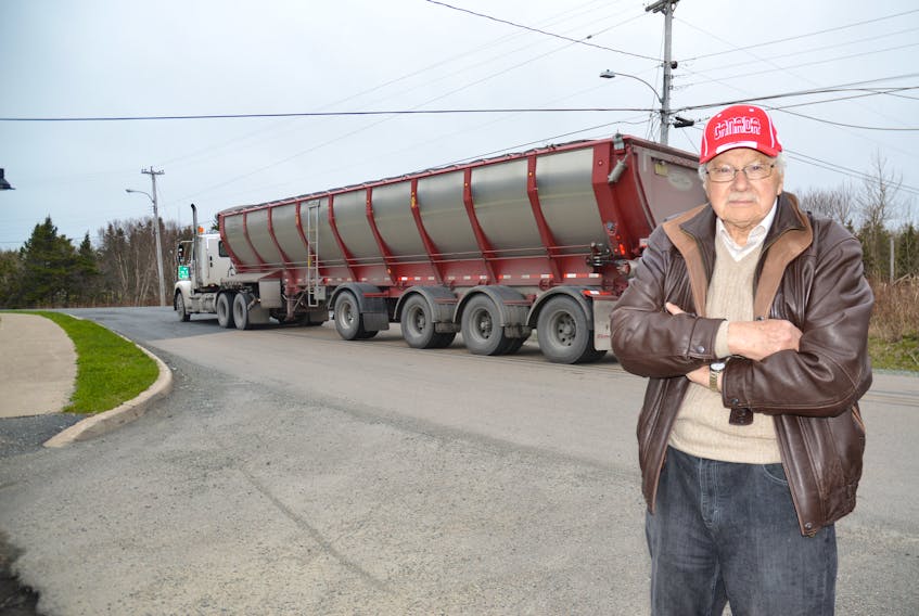 LeRoy Peach, a member of the Port Morien Development Association, stands on Long Beach Road in Port Morien as a truck hauling coal from the Donkin Mine to Sydney passes in the background. Peach said what the trucks are doing to the environment and with safety concerns is not a fair trade off for the jobs the mine has created.